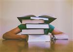 Student behind a stack of five books 